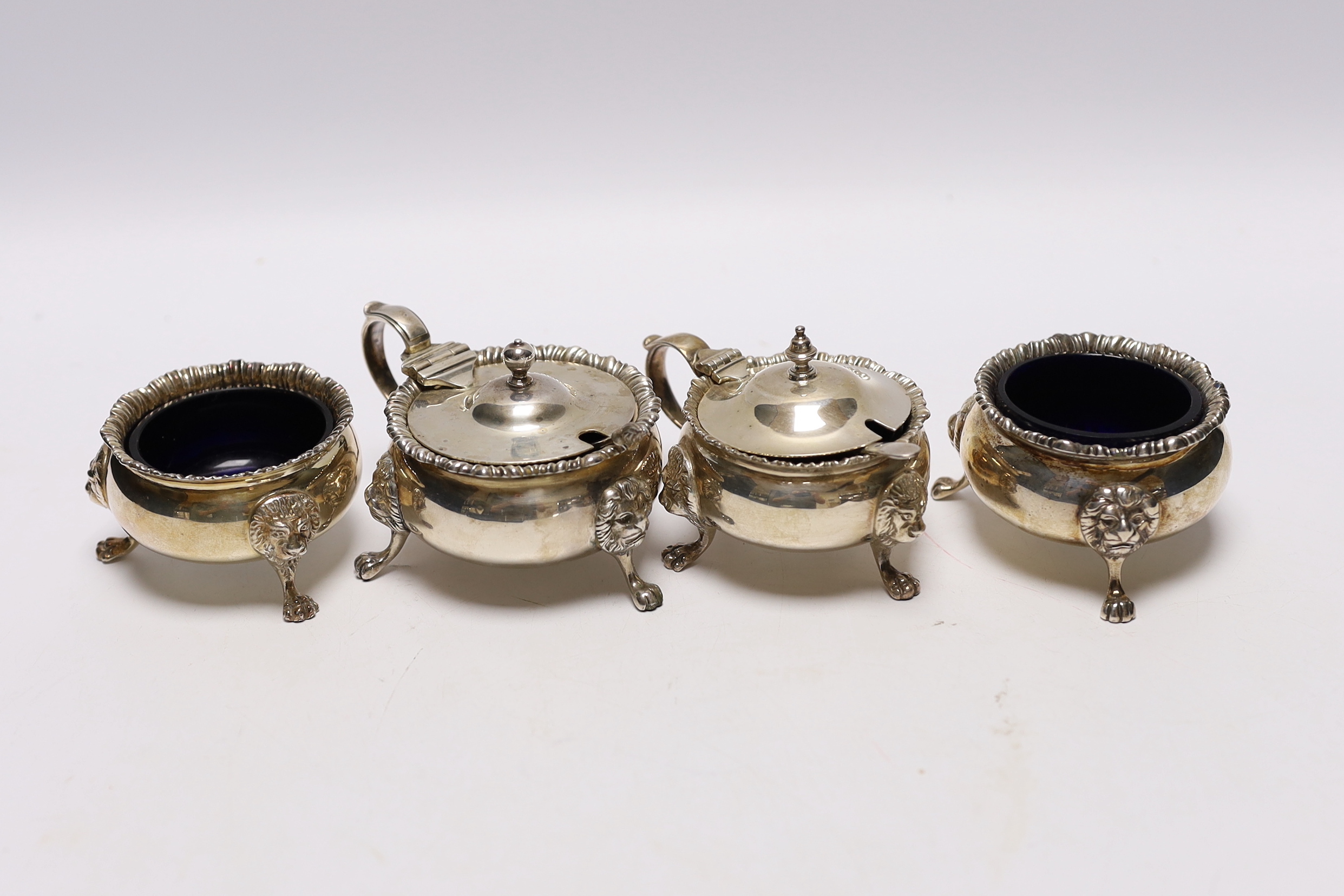 An Elizabeth II silver four piece condiment set by Garrard & Co, London, 1971/73, with blue glass liners and two associated spoons.